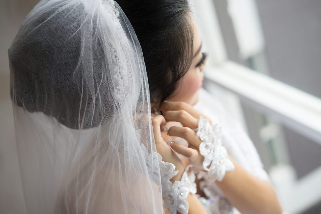 Braut legt Ohrringe an – perfekter Schmuck zum Brautkleid