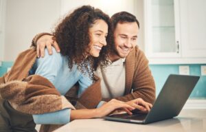 Junges Paar gestaltet Eheringe gemeinsam am Laptop